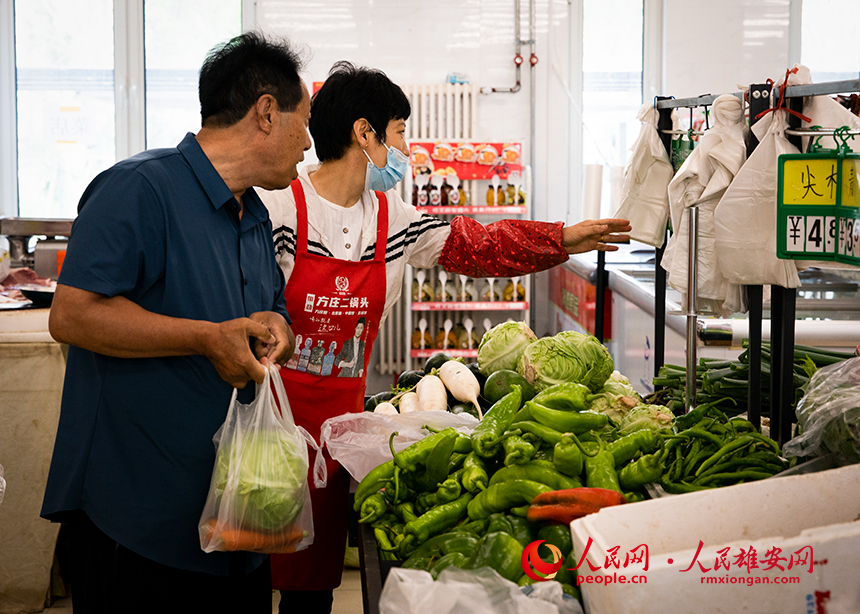 菜店內(nèi)，工作人員正在為顧客提供幫助。出門就是菜店，吃飯不發(fā)愁，成為容東片區(qū)居民的日常。人民網(wǎng)?宋燁文攝