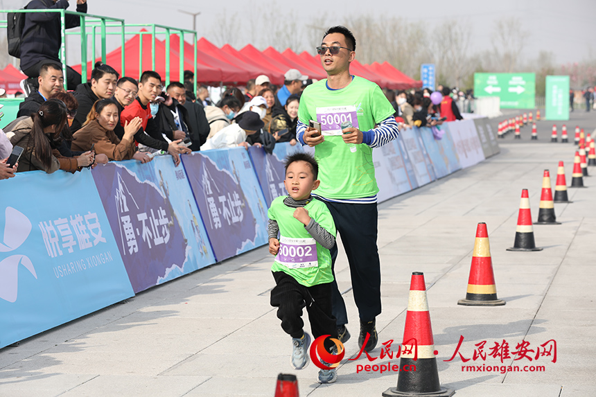 2023雄安半程馬拉松現(xiàn)場，父親帶著兒子參加家庭夢想跑。人民網(wǎng) 李兆民攝