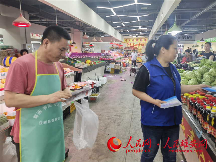 普法活動進市場。安新縣委政法委供圖