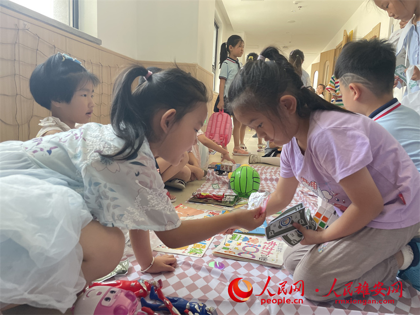 圖為“集市行樂”活動(dòng)中，學(xué)生用“悅?cè)輲拧边M(jìn)行交易。雄安容和悅?cè)萦變簣@供圖