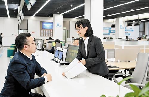11月14日，雄安新區政務服務中心投資建設項目服務區綜合受理窗口，雄安新區建設和交通管理局工作人員張雅然（右）為辦事群眾解疑答惑。 本報記者 劉光昱攝
